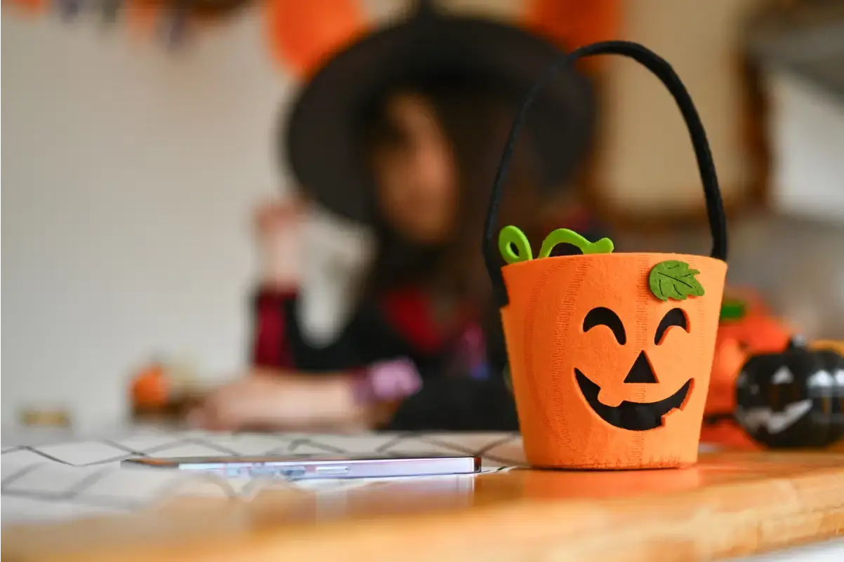 Alt text: Personalized Halloween treat bucket with a smiling jack-o’-lantern design on a table