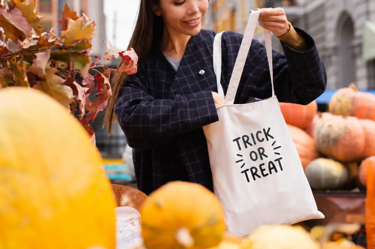 Woman holding a personalized trick-or-treat tote bag at a pumpkin market